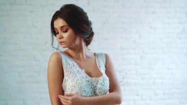 nazik bir saç modeli siyah saçlı güzel bir bayan uzun zarif beyaz giysili bir stüdyoda ayakta, poz, elini kolunu üzerinde tutarak, düşünceli tarafına arıyorsunuz