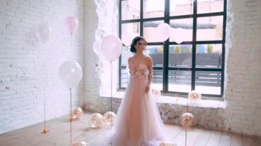 Balonlar, pembe tonları üzerinde video, nazik bir saç modeli ve boş odada altın bir çelenk ile mütevazı bir esmer tarafından çevrili poz görkemli Yunan tanrıçası bahar ışık harika elbise görüntü