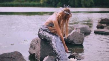 deniz kızı göle bir taş üzerinde oturan uzun kuyruklu ve çiçekler çağrıştırıyor