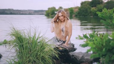 hizmetçi ile sarışın uzun düz saç, bir deniz kızı inci taç kafasını ve bir günlük lake yakınlarında oturan bir lüks gümüş kuyruk saçını, eliyle kusuyor ve geri dönüş düzeltiyor