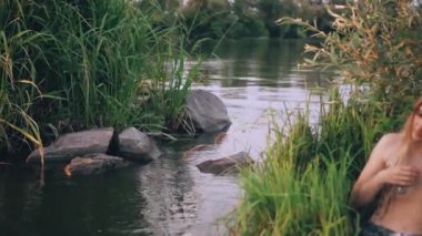 Sarı saçlı ve uzun, mükemmel gümüş kuyruk ile nazik bir siren grass banka nehre yakın oturur ve büyük bir kabuk için onun kulağına koyar, saçları ve okyanus şarkı gülümsüyor düzeltiyor