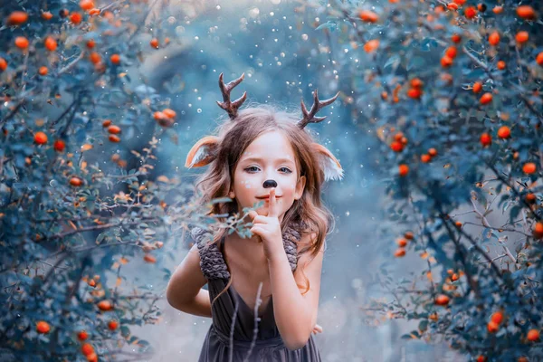 Duch lasu w formie dziecko jasny brązowy sukienka, Jeleń baby figlarnie prowadzi do lasu, mały faun utrzymuje sekret i ukrywa w krzewów jagodowych, kolory zimne zimowe — Zdjęcie stockowe