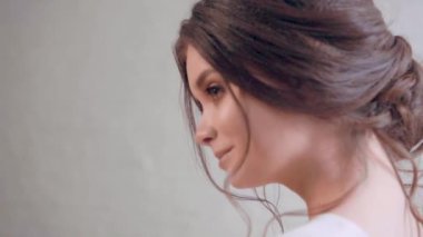 çekici yumuşak özellikleri, kahverengi gözleri ve çıplak makyaj, siyah saçlı sevimli kız portre çekim toplanan içinde hassas saç modeli, yüzünde hafif bir gülümseme kameraya poz dudaklarında bukleler düşmek