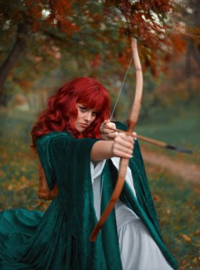 an saldırı, Robin Hood efsanesi önce Kızıl saçlı ateşli soyguncu kız ok ve yay onun elinde tutan, şaşırtıcı pelerin bekliyor ve beyaz ipek pahalı elbise, sıcak renkler, Gotik