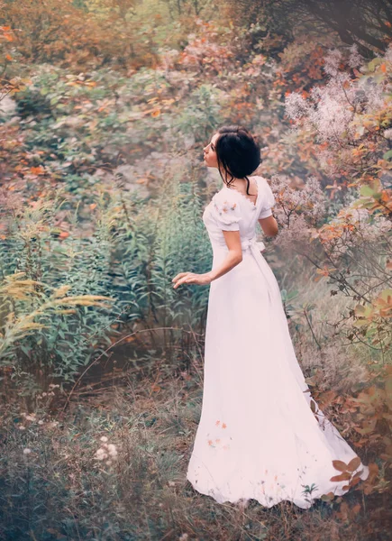 Όμορφη πριγκίπισσα σε ένα μακρύ άσπρο φόρεμα χάθηκε σε ένα μακρινό δάσος, ακούει το θόρυβο και το τραγούδι των πτηνών, στέκεται ακόμα σε αναμονή, μια παραμυθένια νεράιδα σε ένα μακρύ μεταξωτό vintage κομψό λευκό φόρεμα — Φωτογραφία Αρχείου