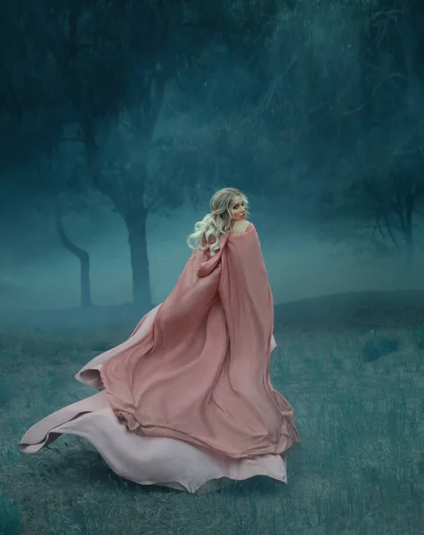 fairy-tale witch with blond hair who runs in a dark and dense mysterious forest full of white mist, dressed in a long, flying and flowing peach rosewood dress and raincoat, woman in the moonlight