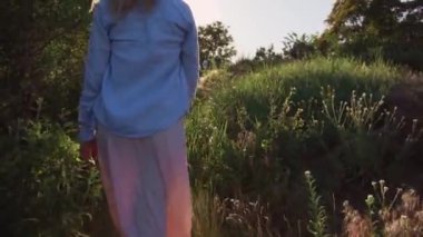 Genç bir kız, bir sarışın pembe elbise ve mavi tişört, ışık boğulmuş bir glade üzerinden yürür ve onun uzun otların vuruş. Rüzgar uzun, kıvırcık saçlı geliştirir. Yeşil yaz arka plan