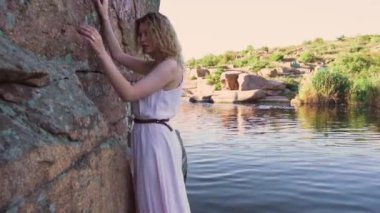 kız taş duvarın üstünde yeşil çim ile şeffaf bir nehir yakınındaki iplik