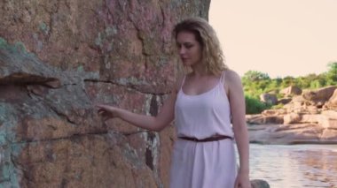 uzun elbiseli bir kız taş taş yürür ve onun parmaklarıyla dokunur