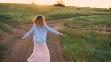 uzun bir pembe dar bir yolda dans çekici ince kız elbise ve ışık mavi gömlek, eğlenceli ve incelikle iplik, kalıp ve parlak güneşin kırsal kadın sarışın saçları