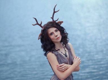 Anne geyik lagle Gölü, karakterler peri ormanın, görüntü üzgün kadın-Faun yakın büyük bir göl, ev yapımı boynuzları ve siyah kıvırcık saçlı kulaklara sıra dışı makyaj önünde ilginç fotoğraf