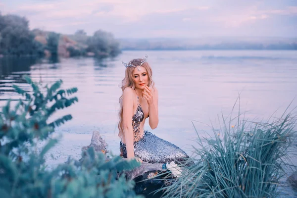 Reina del mar tristemente mira hacia abajo y piensa durante mucho tiempo, encantadora dama rubia delgada pensada cuidadosamente, foto de arte en tonos fríos, sirena con una larga cola plateada, imagen de personaje mítico —  Fotos de Stock