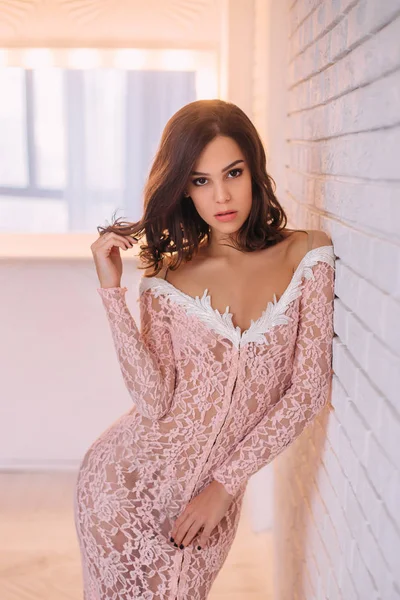 Luxurious brunette girl, with a bob haircut, posing in an expensive, pink dress with an open back. The princess in the white room. Scandinavian minimalist style interior. Image for prom and party — Stock Photo, Image