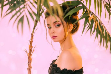 moda model parlak renk pembe arka plan, palmiye dalı yaprak yaratıcı trendy Makyajlı seksi kız portresi poz. bukleler, çıplak ihale omuzlar asılı iki buns ile ilginç saç modeli