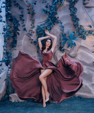 muhteşem ressamın, marsala uzun saten elbise gibi çırpınan uçan gibi ince çekici Bayan boya konturları, seksi kız zarif onu silah top gri topuklar çıplak bacaklar çekici gösterir kaldırdı.