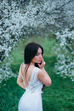 Harika çekici Bayan koyu siyah uzun saçları ve gözleri aşağı bakıyor, standları çiçek açan Manolya, lüks, giyen yanında nefis elbise ile açık bir arka beyaz mavi parlak renkler sıcak.