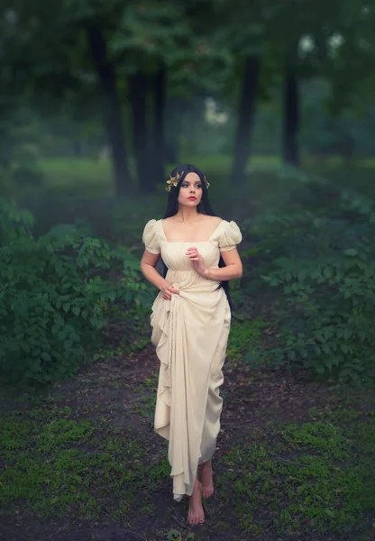 A titokzatos hercegnő egy fehér vintage ruha elveszett egy mesebeli elvarázsolt erdő. Hosszú, fekete haja az arany koszorú díszíti. Érzelmek, félelem és a kíváncsiság. Fotó Art — Stock Fotó