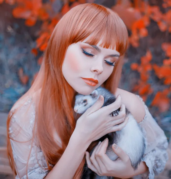 Jasne zdjęcie, rudowłosa dziewczynka z prostymi włosami i grzywką posiada uroczy fretka spania w jej ręce, Pani z zamkniętymi oczami przedstawia wariant makijaż jesień, liście tło Las — Zdjęcie stockowe