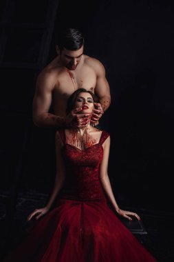 Lanet olası vampir, kız ve adam onu kollar, göğüs ve yüz, oyun korkunç hikayeler kırmızı kanlı karanlık odada ile şeytan, kırmızı uzun elbise ve başını tutan adam seksi Bayan ile aşk hikayesi