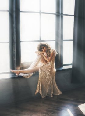 güzel Bayan uzun ışık şeffaf dantel elbise beyaz sis ve yıldırım ışık, yeni doğan bir melek, bir loft tarzı geniş bir odada büyük bir pencerede yakınındaki bir kız gibi yumuşak bukleler