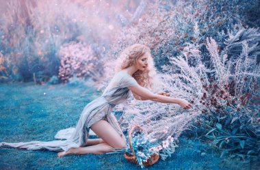 alan deniz kızı otlar ve küçük sepette çiçekler toplar. diz açık çıplak bacaklar ve sırt, parlak güneşin altında büyülü mor ve mavi glade parlama ile uzun ışık elbiseli ince orman perisi oturur