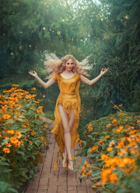 Mysterious attractive flower fairy in light yellow dress with long train and open legs in jump in the forest with bright flowers. lady with blond hair flying in bright sunlight, art processing photo clipart