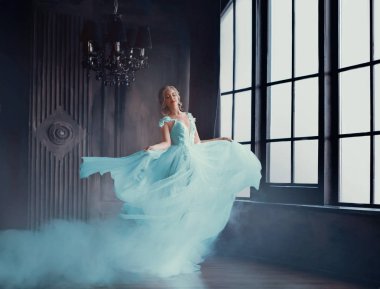 Cinderella sihirli dönüşüm içine lüks elbiseli güzel bir prenses. Genç kadınlar iplik ve bir odada karanlık, kasvetli, anında çırpınan elbise dans sarışın, vardır. Sanat fotoğraf