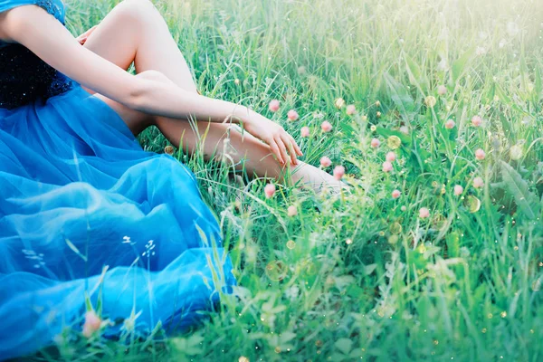 Очаровательный нежный художественное фото с творческими цветами, дама касается пальцев руки ее сексуальные голые ноги, принцесса в длинной синей пышной шикарное элегантное платье, свободное место для текста, без лица — стоковое фото