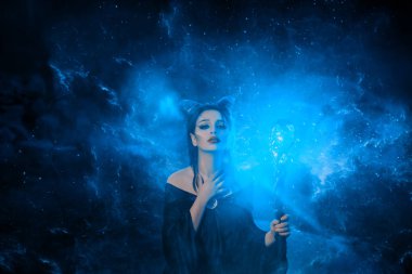 gizemli karanlık elf korkunç lanet var, baş boynuzları ile büyüleyici kız ve elinde parlayan köpüklü sihirli sopa, yeşil elektrik ateş lanet bayan boynuna elini koyar, yaratıcı sanat fotoğrafı