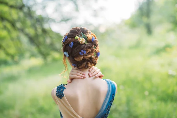 Ovanlig cool chic frisyr för långt mörkt hår, arbete av frisör, bild för examen och bröllop, Forest nymf med blommor i en frisyr, mild bild, en konst foto från baksidan utan ansikte — Stockfoto