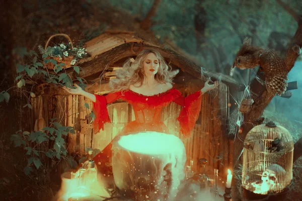 Witch in a red dress with bare shoulders of the Baroque era, is preparing a poison. The sorceress calls upon the powers of magic the mentality fills her potion. with a gust of wind her hair flies away — 스톡 사진