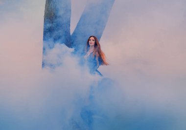 kırmızı turuncu parlak saçlı gizemli mistik bayan, kalın beyaz sis uzun dantel zarif kraliyet elbisegenç bir çekici kadın, duman arasında yangın, yoğun ormanda büyüleyici bir cadı