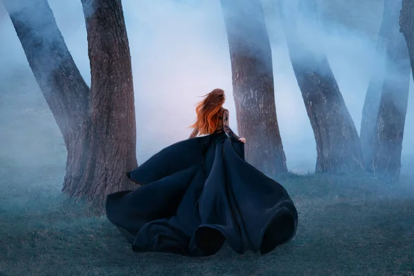 Black widow in a long dark silk lace dress, a girl with gorgeous light red hair runs off into a secret forest, the sorceress turns into a wild flower, queen of night hiding from the morning sunlight Stock Picture