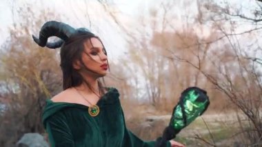 kötü sihirli kraliçe düşmana karşı büyü oluşturur, uzun yeşil zümrüt elbise manto siyah cadı yerde sihirli sopa yener, uçan koyu saç ve yaratıcı makyaj ile bayan portre çekim