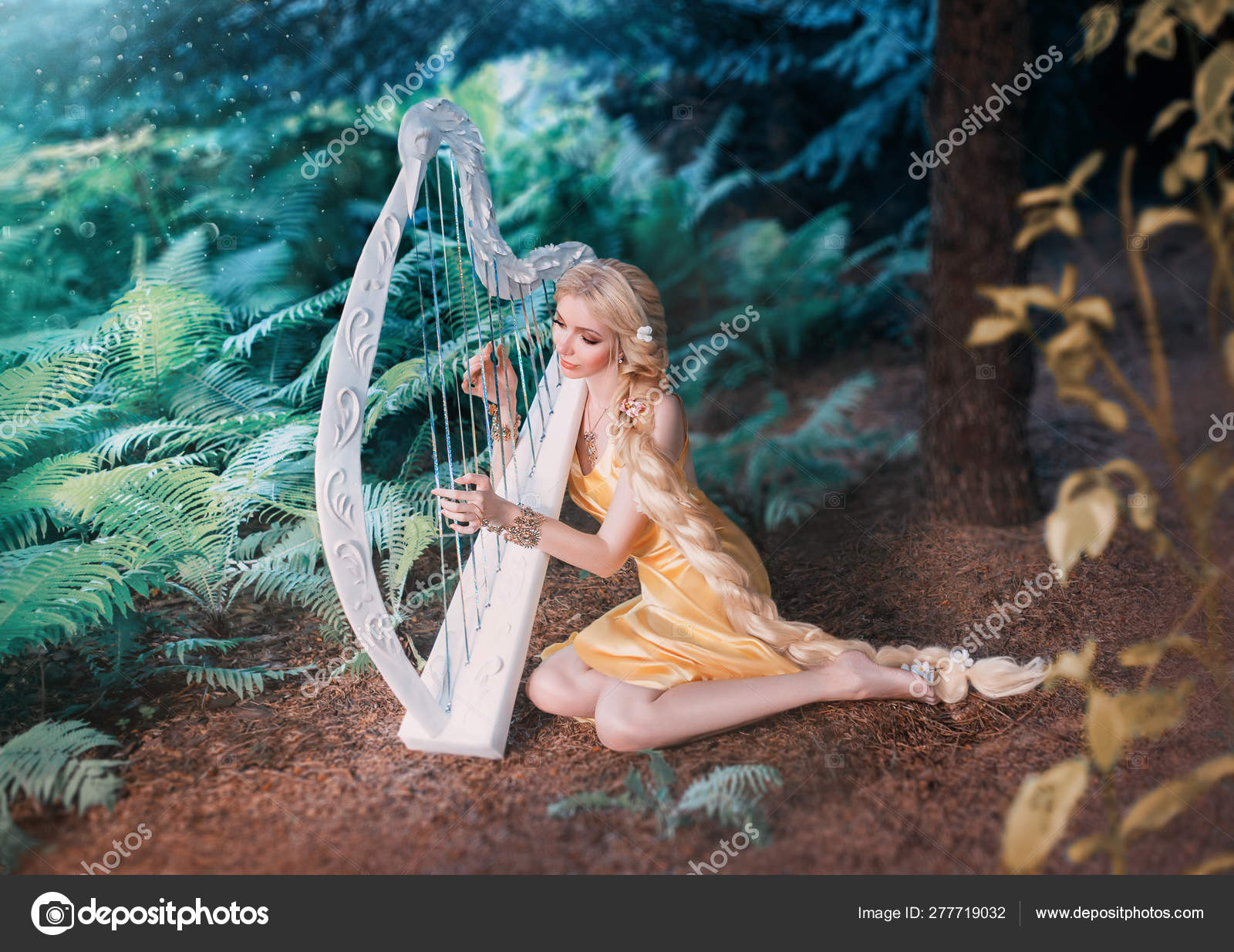 Сказочный лесной эльф сидит под деревом и играет на белой арфе, девушка с длинными светлыми волосами плетена в длинном желтом платье, летняя богиня отдыхает и поет под звуки волшебного музыкального инструмента стоковое