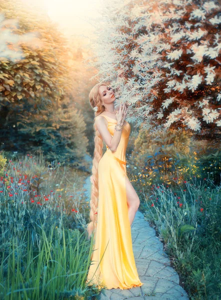 Humanisation de la lumière du soleil, fille mince dans magnifique robe jaune séduisante douce de l'époque Renaissance, dame aux longs cheveux blonds, reine de l'été réveille les plantes après un long froid avec chaleur — Photo