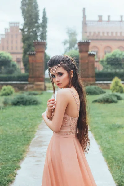 Retrato de uma princesa triste, solitária e assustada que fica congelada e molhada na chuva torrencial. Incrível, rosto bonito com olhos grandes, maquiagem suave. Tiara no cabelo. Fica no caminho da propriedade. . — Fotografia de Stock