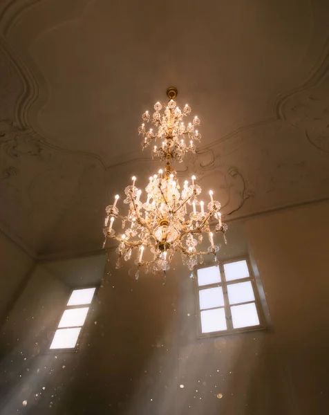 Une pièce fabuleuse avec un cristal luxueux, lustre antique au plafond avec ornement en dentelle et moulage en stuc de plâtre vintage. La lumière magique du soleil déverse des rayons doux de la fenêtre — Photo