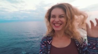 Neşeli sarışın bir kadın selfie videosu çekiyor, atlıyor, büyük bir feribotta gülüyor. Genç bir kız blogcu izleyicileriyle iletişim kurarak tatilini denizde büyük bir gemiden yayınlıyor. Öpücükler merhaba der