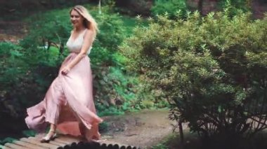 Dalgalı saçlı, uzun elbiseli, hareketli sarışın bir kadın. Beyaz dantelli bluz ve pembe ipek etek. Modern mutlu gelin. Georgia 'daki yeşil parkta keyifli bir yürüyüş..