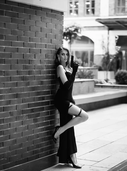 Hermosa joven con un vestido elegante. Mujer sosteniendo un arma en sus manos. Modelo de moda en forma de un peligroso espía sexy. Fotografía en blanco y negro. Señora retro, peinado vintage maquillaje de noche —  Fotos de Stock