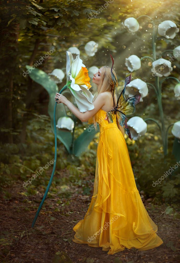 Fantasia donna bionda foresta fata. Modello di moda in un abito lungo  giallo con ali di