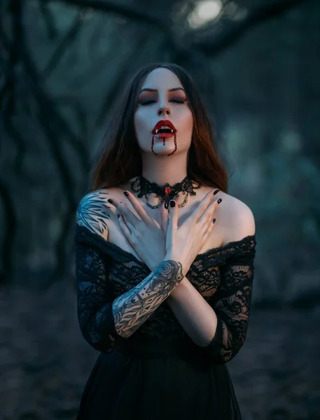 Séduisante femme vampire sexy avec des dents acérées croque des gouttes de sang coulant sur les lèvres rouges. Gros plan portrait de la belle bouche. Maquillage d'art festif. Cravate en dentelle gothique sur le cou. Médiéval fille sexy — Photo