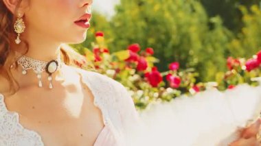 Portre yakın plan kırmızı dudaklı klasik bayan prenses elinde yelpaze, taze hava, sıcak yaz havası sallıyor. fantezi ortaçağ kadın kraliçesi vücudu kısmen eski tarz beyaz elbise seti