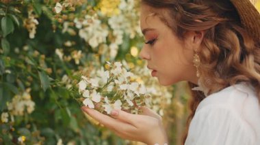 Sanat portresi yetişkin mutlu kız eli yeşil yapraklara dokunuyor beyaz çiçek ağacı. Eski moda kadın tarzı bahar doğasının tadını çıkar. Genç bir kadın yüzünü kapatır burnunu koklar çiçek kokusu kokar.