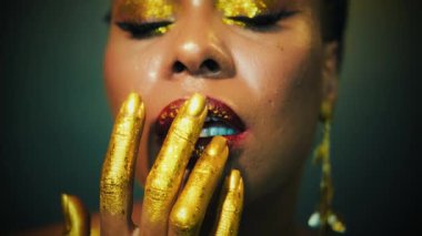 Yakın plan güzellik sanat portresi altın akşam makyajı Afro-Amerikan mutlu kadın, dudak derisi boyalı altın sarısı eller. Seksi gülümseyen peri kız pozu veren manken. Parıldayan gölgeli gözler.