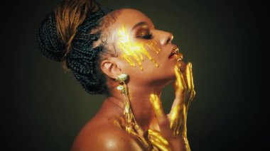Fantezi sanat portresi dudaklar gözleri kapar Afro-Amerikan kadın yüzünü. Profesyonel yaratıcı altın makyajlı parlak gölgeler. Altın sarısı damlalar içinde eller, seksi manken güzel kız. Stüdyo siyah