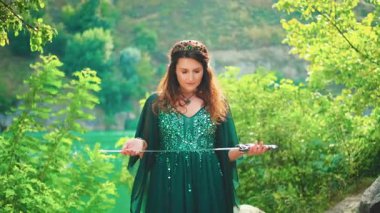 Savaştan önce dua eden, elinde gümüş kılıçla savaşan kızıl saçlı, fantezi portresi. Kurban etme ayini. Yeşil ipek elbise uzun elf kollu altın taç zümrüt mücevher ortaçağ tarzı