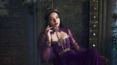 Güzellik portresi fantezi kadın şeytani elf kraliçesi tahtta oturuyor, karanlık gotik odada. Seksi yüz kapalı cadı kız yaratıcı makyaj, sivri kulaklar. Gotik vampir prenses, altın taç. Eski tarz oda.