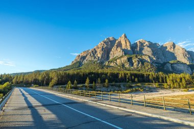 Dolomit İtalya Alpleri'nde. Güzel bir gün. Kalker ve dolomit kayaları dibinde iğne yapraklı ormanlarda yol geçmektedir. Aktif ve araba turizm kavramı